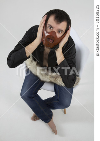 young man with a mask on his face sits in a white 50168225