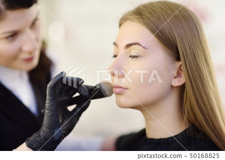 Beautician applying the tone of the foundation Beautician applying the tone of the foundation 50168825