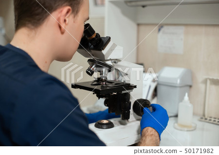 Laboratory assistant looking through microscope. Laboratory assistant looking through microscope. 50171982