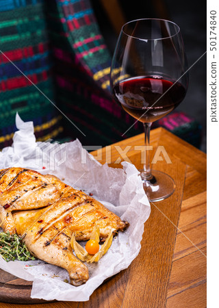 Grilled chicken and glass of red wine of the interior in the restaurant. Grilled chicken and glass of red wine of the interior in the restaurant. 50174840