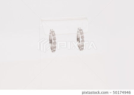 Pair of white golden diamond earrings on transparent stand. Golden earrings with diamonds, luxury Pair of white golden diamond earrings on transparent stand. Golden earrings with diamonds, luxury 50174946
