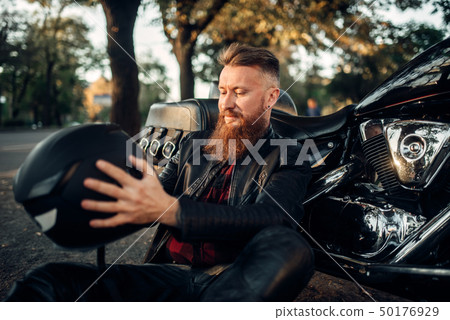 Biker sitting on the ground against his chopper Biker sitting on the ground against his chopper 50176929