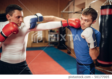 Two male kickboxers practicing on workout in gym 50177005