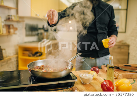 Chef salted meat with vetables into the frying pan Chef salted meat with vetables into the frying pan 50177380