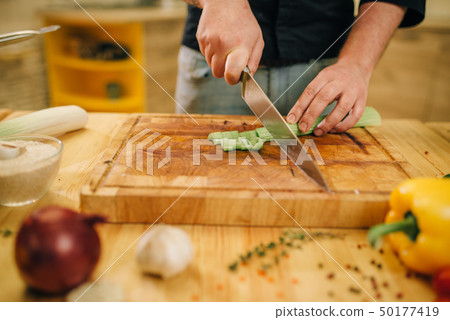 Male person cooking meat with vegetables in a pan Male person cooking meat with vegetables in a pan 50177419