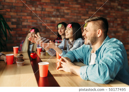 Smiling friends playing sticker notes to forehead 50177495