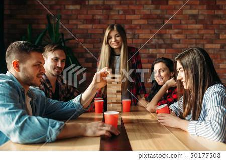 Friends plays table game, selective focus on tower 50177508