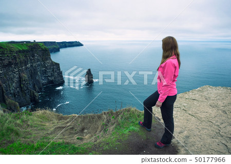 Young girl standing at the cliffs of Moher Young girl standing at the cliffs of Moher 50177966
