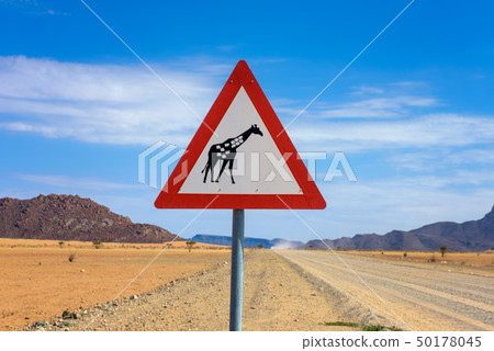 Giraffes crossing warning road sign placed in the desert of Namibia 50178045