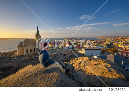 Tourist on top of a hill enjoys the view of Luderitz in Namibia at sunset 50178051