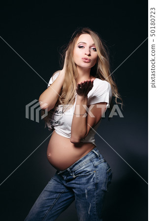 Gorgeous expectant mother with naked tummy blowing 50180723