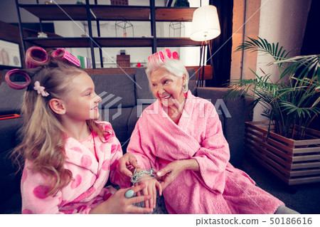 Girl and her granny wearing hair rollers feeling happy together 50186616