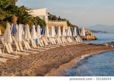 Summer sunrise on coast, Corfu island, Greece. Beach with Sunbeds and umbrellas with perfect views 50188044