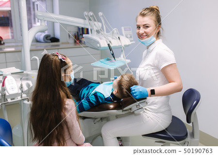 Little girl help female dentist, new teeth examinationand treatment of cavities Little girl help female dentist, new teeth examinationand treatment of cavities 50190763