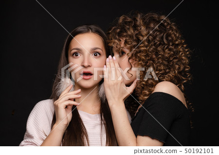 Shocked brunette posing while friend whispering 50192101