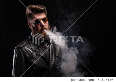 Handsome bearded man with leather jacket wearing cool glasses over black background Handsome bearded man with leather jacket wearing cool glasses over black background 50196136