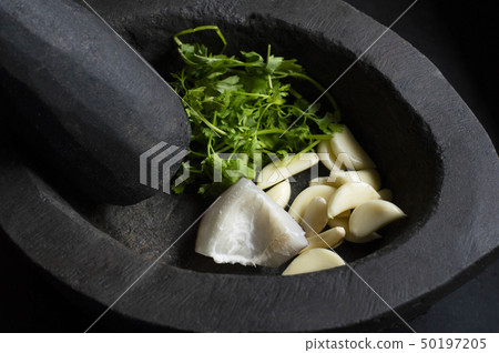 Stone mortar & pestle with garlic, coconut slices 50197205
