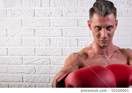 Portrait of handsome boxer man standing on the bric wall and looking at camera with intense gaze Portrait of handsome boxer man standing on the bric wall and looking at camera with intense gaze 50200061
