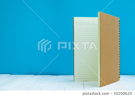 Blank notebook on white wood table front blue wall Blank notebook on white wood table front blue wall 50200629