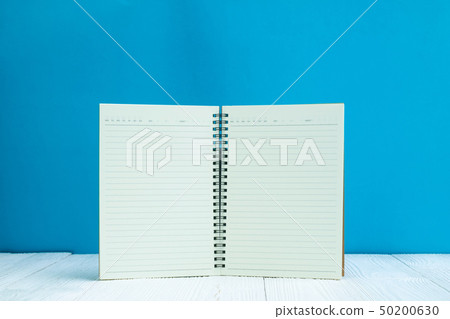 Blank notebook on white wood table front blue wall Blank notebook on white wood table front blue wall 50200630