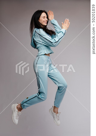 Happy brunette jumping and laughing in studio 50201839