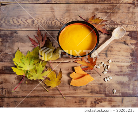 Flat lay pumpkin soup bowl on rustic wooden background Flat lay pumpkin soup bowl on rustic wooden background 50203233