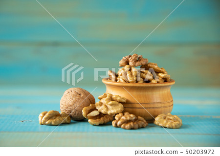 Walnuts on blue rustic table in wooden bowl Walnuts on blue rustic table in wooden bowl 50203972