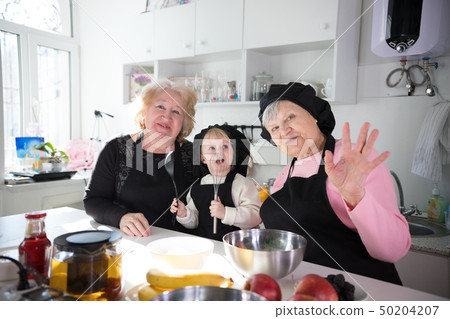 Family eating pancakes and drinking tea in the kitchen. Posing for the camera and waving hands 50204207