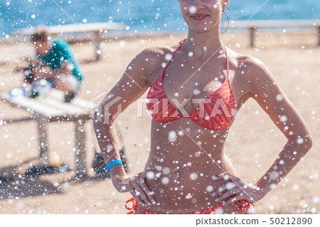 Beautiful and young smiling girl in a striped orange swimsuit stands against the backdrop of the Beautiful and young smiling girl in a striped orange swimsuit stands against the backdrop of the 50212890