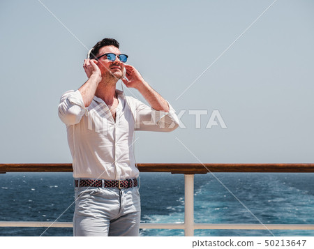 Fashionable man listening to music in white Fashionable man listening to music in white 50213647