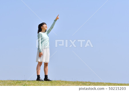 Girl pointing in the blue sky Girl pointing in the blue sky 50215203