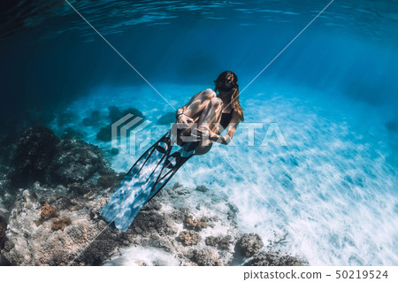 Woman freediver with fins swim in blue sea Woman freediver with fins swim in blue sea 50219524