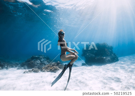 Woman freediver posing over sandy sea with fins Woman freediver posing over sandy sea with fins 50219525