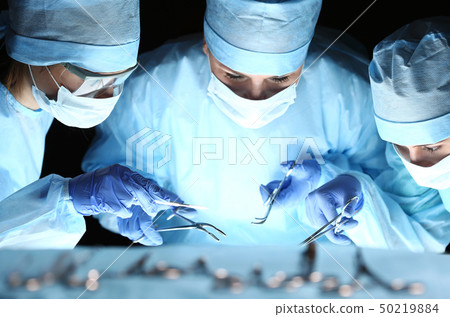Group of surgeons at work operating in surgical theatre Group of surgeons at work operating in surgical theatre 50219884