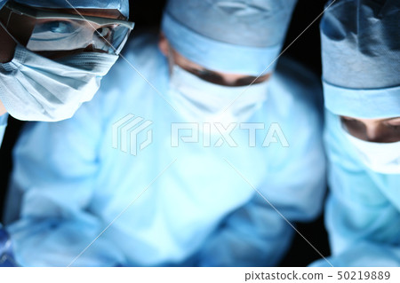 Group of surgeons at work operating in surgical theatre 50219889
