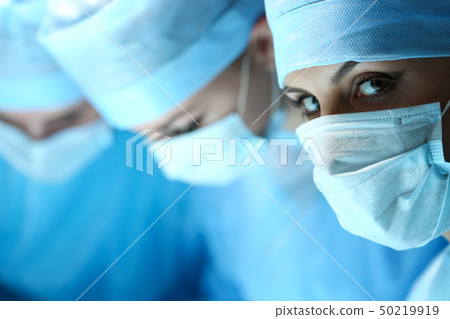 Three surgeons at work operating in surgical theatre Three surgeons at work operating in surgical theatre 50219919