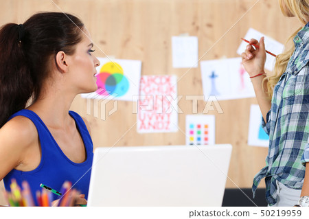 Two female designers in office looking at wall Two female designers in office looking at wall 50219959