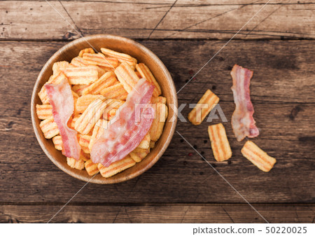 Bacon flavoured snacks chips in wooden bowl with 50220025
