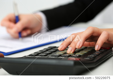 Female accountant hand holding pen counting on calculator Female accountant hand holding pen counting on calculator 50220075