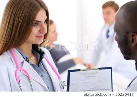 Two doctors share and discuss important document on clipboard pad Two doctors share and discuss important document on clipboard pad 50220417