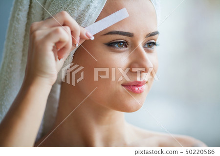 Beautician waxing young woman's eyebrows in spa center Beautician waxing young woman's eyebrows in spa center 50220586