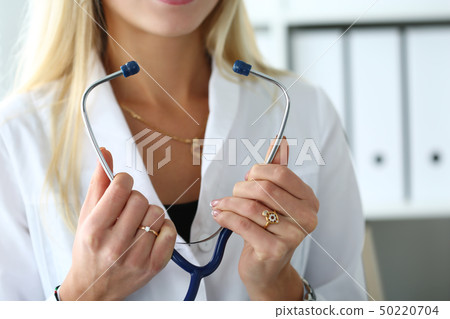 Female doctor hands holding stethoscope in front of chest 50220704