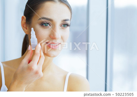 Health and Beauty. Eye Care. Beautiful Young Woman Holding Drops 50223505