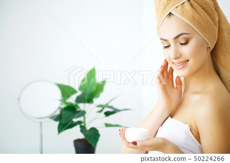 Woman hold cosmetic cream. Beautiful face young model. 50224266