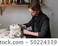 Young male tailor sewing fur on furrier machine 50224339