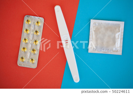 Pregnancy test. The result is positive with two strips and condom with contraceptive on colored Pregnancy test. The result is positive with two strips and condom with contraceptive on colored 50224611