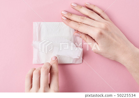 Woman hands hold sanitary pad on a pink background 50225534
