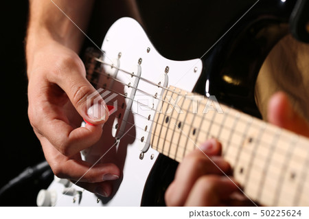 Male hands playing electric guitar with plectrum closeup Male hands playing electric guitar with plectrum closeup 50225624