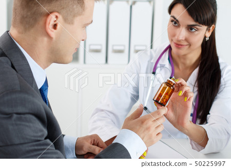 Beautiful female medicine doctor giving pills to male patient  50225997
