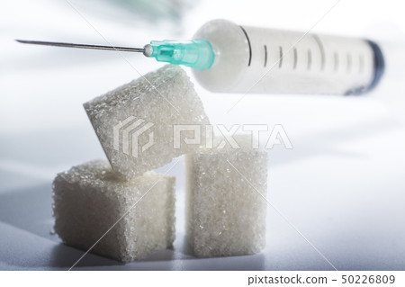 syringe filled with sugar lies on solid sugar cubes on white background 50226809